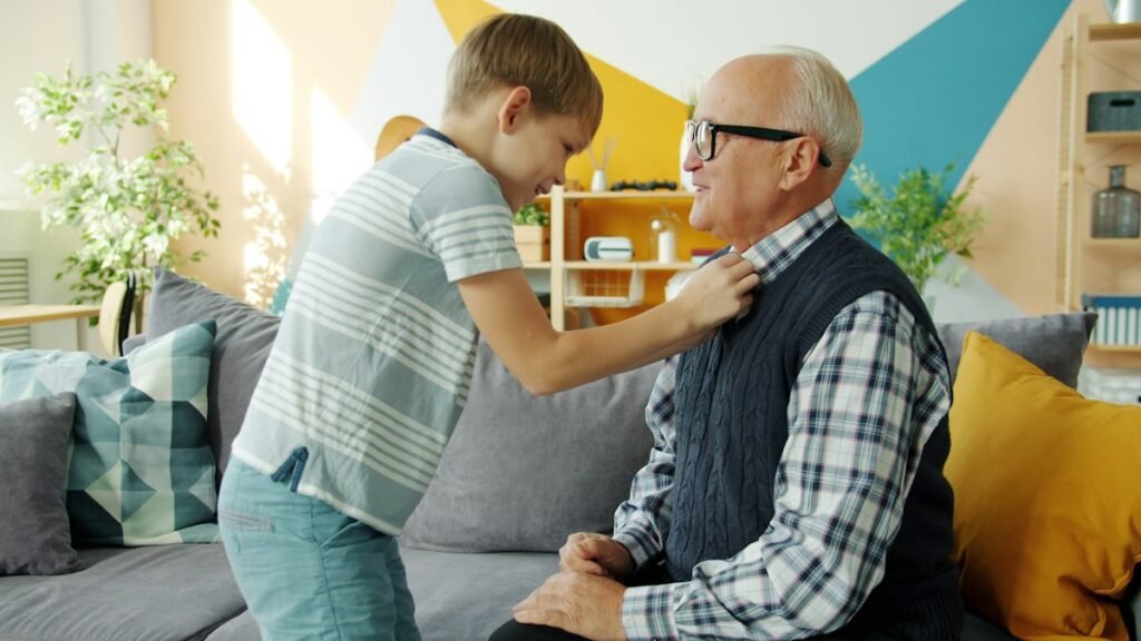 Grandson helping his elderly grandfather get dressed at home
